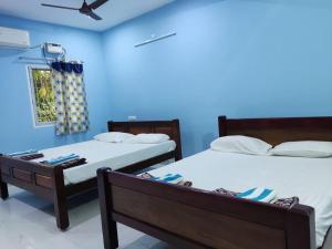 蓬蒂切里Sri Sai Farm House的蓝色墙壁客房的两张床