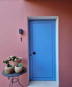阿尔戈斯托利翁Julietta Suites的粉红色墙壁上的蓝色门,桌子上挂着植物