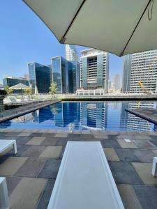 迪拜Wonderful Reva Aparthotel Downtown的坐在城市游泳池旁的白色长凳