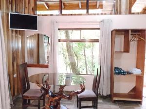 蒙泰韦尔德哥斯达黎加Casitas del Bosque Monteverde.的一间设有玻璃桌、椅子和窗户的用餐室
