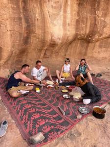 瓦迪拉姆Wadi Rum Quiet Sky的一群人坐在毯子上吃着食物