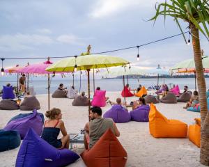 吉利阿尔吉利郎邦简易别墅的一群人坐在海滩上,在遮阳伞下