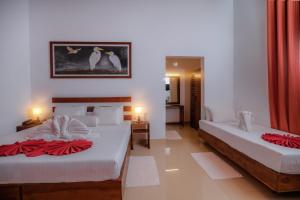 锡吉里亚Sigiri Asna Nature Resort的一间带两张床的卧室和一间带两张桌子的房间