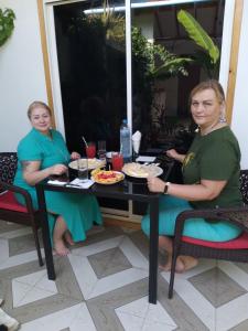 图杜Thoddoo Haisha inn, Maldives的两个坐在桌子上的女人,上面有食物