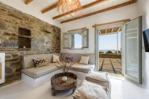 帕罗斯岛Parian Philoxenia Villa, Santa Maria Beach的客厅设有石墙和沙发。