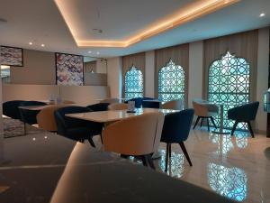 多哈C - Hotel and Suites Doha的餐厅设有桌椅和彩色玻璃窗。