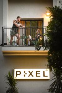 特拉维夫Pixel Dizengoff Square - Smart Hotel by Loginn Tel Aviv的两人坐在大楼的阳台上