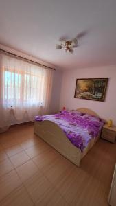 GreciCasa Caraua的一间卧室配有一张带紫色床单的床和天花板