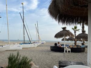 圣罗克Sotogrande Paseo del Mar - 10 steps away from the beach的一群人坐在海滩上的伞下