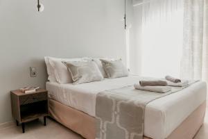 特里卡拉Quattro Luxury Apartments的白色的床、白色枕头和窗户