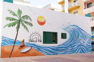 阿罗纳Single Fin Hostel的一座建筑的一侧棕榈树的壁画
