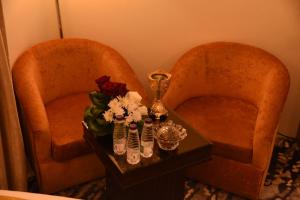 麦地那Al-Andalus Palace Golden的两把椅子和一张桌子,上面有鲜花和花瓶