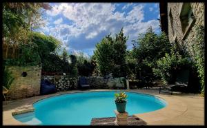 贝尔南Lion-Les Jardins de Kuz的蓝色的游泳池,旁边是盆栽植物