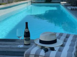 开普敦Sea Five Boutique Hotel的游泳池畔的帽子和一杯葡萄酒