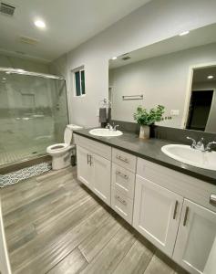 洛杉矶Cheers Hostel的一间带两个盥洗盆、淋浴和卫生间的浴室