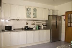 丰沙尔Ivone Madeira Guest House的厨房配有白色橱柜和不锈钢冰箱