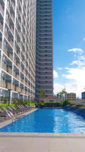 马尼拉StayInMyCondo - 8th Condo in Pasay near NAIA Airport, MOA Pasay的一座大型建筑,在一座建筑前设有一个游泳池