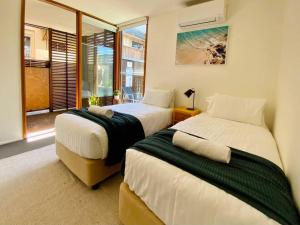 拜伦湾Poolside Apartment In Central Byron的一间卧室设有两张床和窗户。