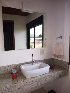 塞尔苏拉穆斯州长镇Pousada Divino Oleiro - Gov. Celso Ramos的浴室设有白色水槽和镜子