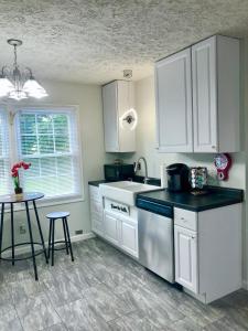 布卢明顿Trestle Creek Farm- farmhouse suite的厨房配有白色橱柜、水槽和桌子