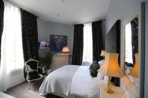 伦敦皇冠和皇权酒店的一间卧室配有一张床、一把椅子和窗户。