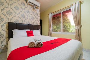 雅加达RedDoorz near Tomang 2的一间卧室配有一张带红色毯子的床和窗户。
