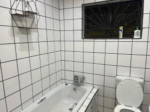 PimvilleMaponya Guest House的白色瓷砖浴室设有浴缸和卫生间。