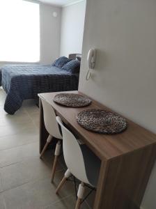 特木科Departamento Estudio en pleno centro de Temuco的客房设有一张桌子、两把椅子和一张床