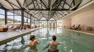 尚蒂伊Le Grand Pavillon Chantilly的两人在大楼的游泳池游泳