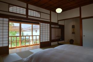 仓敷滔々 倉敷民藝館南の宿 toutou, Mingeikan Minami no Yado的一间卧室设有一张床和一个大窗户