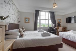 布雷肯The Castle Of Brecon Hotel, Brecon, Powys的一间卧室设有两张床、一张桌子和一个窗口。