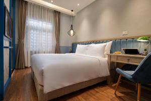 河内HANOI FLORA HOTEL的一间卧室配有一张床、一张桌子和一把椅子