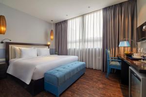 河内HANOI FLORA HOTEL的酒店客房设有一张大床和一张书桌。