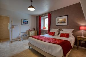 CarluxDomaine des Pierres Blanches - Chambres d'Hôtes的一间卧室配有一张带红色枕头的大床