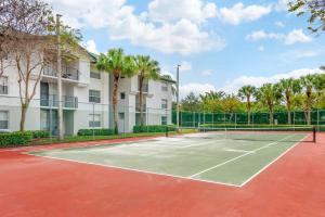 戴维Bright and Modern Apartments at Palm Trace Landings in South Florida的一座棕榈树建筑前的网球场