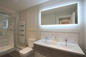 邓斯特布尔Harper Luxe Serviced Apartments Dunstable的一间带水槽、卫生间和镜子的浴室
