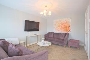 邓斯特布尔Harper Luxe Serviced Apartments Dunstable的客厅配有两张紫色沙发和一台电视机