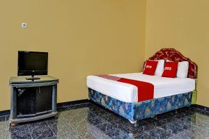 CikampekSPOT ON 91798 Hotel Grand Mutiara的一间卧室配有一张带电视的床和一张高品质的床铺。