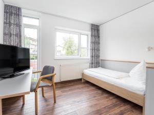萨尔茨堡克尔品豪斯萨尔兹伯格酒​​店的一间卧室配有一张床、一张书桌和一台电视。