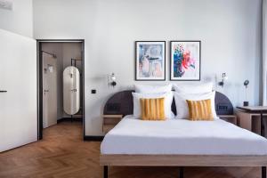 柏林numa I Novela Rooms & Apartments的卧室配有带橙色枕头的大型白色床