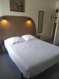 Breuillet努沃莫德酒店的卧室配有一张带白色床单和枕头的大床。