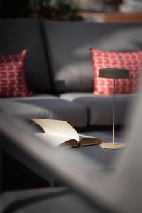 那不勒斯Caracciolo 13 Rooftop & Suites的沙发旁的台灯和一张桌子上的一本敞篷书