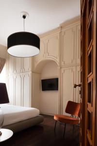 那不勒斯Caracciolo 13 Rooftop & Suites的一间卧室配有一张床、一把椅子和一盏灯