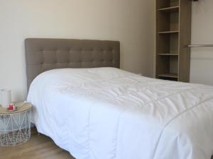 卡布尔Maison de vacance的卧室配有白色床和棕色床头板