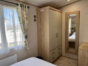 尚克林3 Bedroom Caravan MC34, Lower Hyde, Shanklin, Isle of Wight的一间卧室配有木制橱柜和镜子