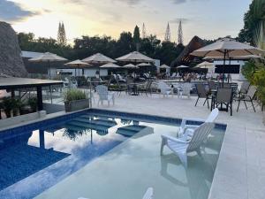 阿纳波伊马拉玛西亚精品酒店的一个带白色椅子、桌子和遮阳伞的游泳池