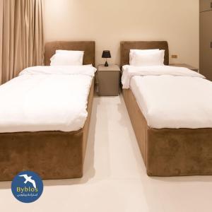 阿尔哈德Byblos Villa Resort的配有白色床单的客房内的两张床