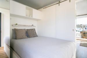 阿尔布费拉The Homeboat Company Albufeira的卧室拥有白色的墙壁,配有一张带两个枕头的床