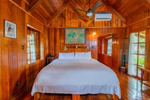 科罗尔Palau Carolines Resort的木制客房内的一间卧室配有一张大床
