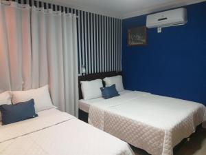 伊塔佩马Casa 1 Encanto dos Mares的蓝色墙壁客房的两张床